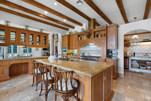 kitchen with visible vents, light stone countertops, brown cabinets, stone tile flooring, and a sink