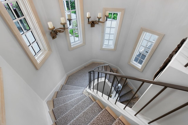 stairs featuring a towering ceiling, carpet flooring, and an inviting chandelier