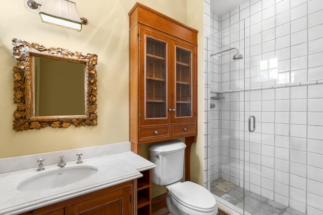 bathroom with a shower with door, toilet, and vanity