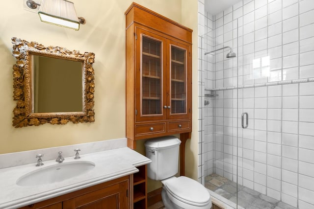 full bath featuring a stall shower, toilet, and vanity