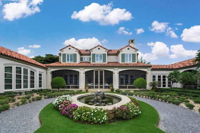 rear view of property featuring french doors, a chimney, and a tile roof