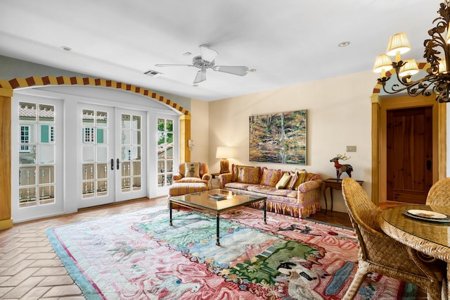 living room featuring a wealth of natural light, ceiling fan with notable chandelier, and french doors