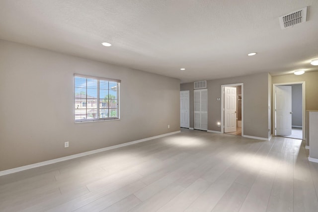 unfurnished room featuring light wood finished floors, visible vents, recessed lighting, and baseboards