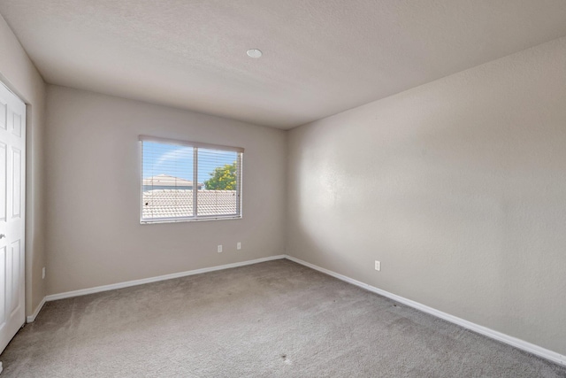 spare room with baseboards, carpet floors, and a textured ceiling