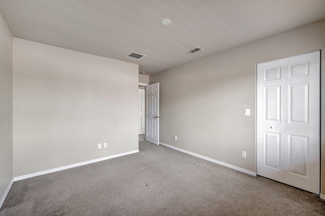 carpeted spare room featuring visible vents and baseboards