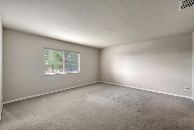 unfurnished room with visible vents, carpet flooring, a textured ceiling, and baseboards