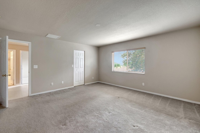 empty room with carpet flooring, baseboards, and a textured ceiling