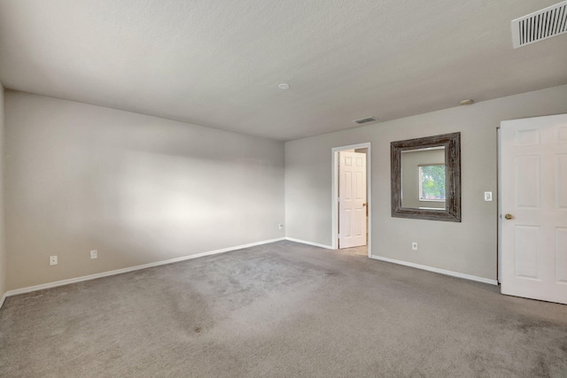 empty room featuring visible vents, baseboards, and carpet floors