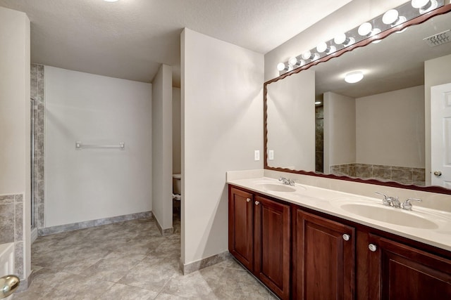 full bath with a sink, visible vents, walk in shower, and double vanity