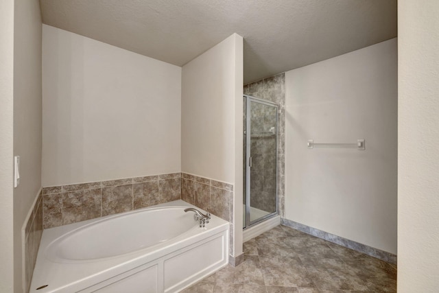 full bath featuring a garden tub, baseboards, a shower stall, and a textured ceiling