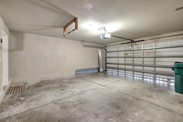 garage featuring a garage door opener and concrete block wall