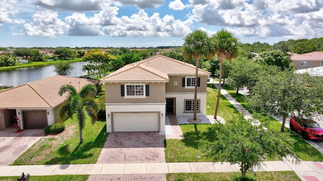 view of front of house with a front yard, stucco siding, a water view, a tiled roof, and decorative driveway