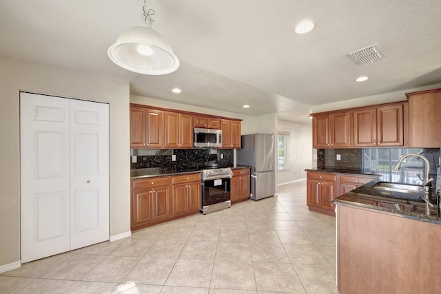 kitchen featuring visible vents, brown cabinets, a sink, stainless steel appliances, and light tile patterned floors