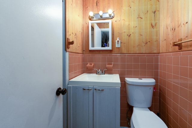 bathroom featuring vanity, tile walls, and toilet