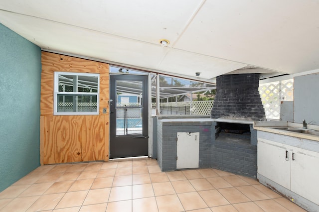 kitchen with white cabinets, light tile patterned flooring, vaulted ceiling, and sink