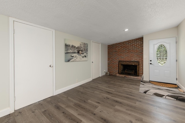 unfurnished living room featuring a textured ceiling, a fireplace, vaulted ceiling, and dark hardwood / wood-style floors