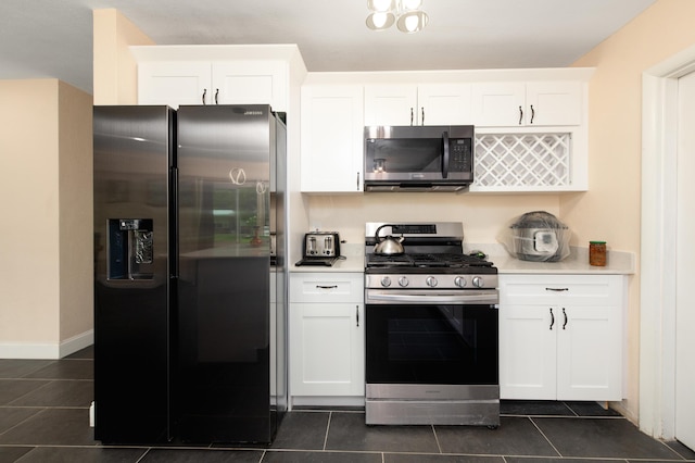 kitchen featuring dark tile patterned floors, white cabinetry, and stainless steel appliances