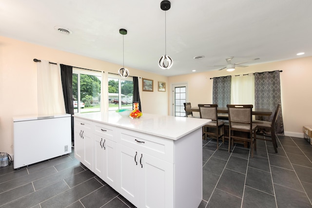 kitchen with ceiling fan, dark tile patterned floors, fridge, decorative light fixtures, and white cabinetry