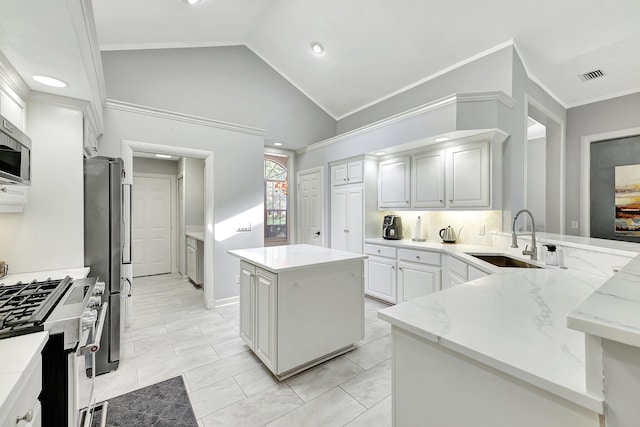 kitchen featuring a kitchen island, appliances with stainless steel finishes, sink, white cabinets, and light stone counters