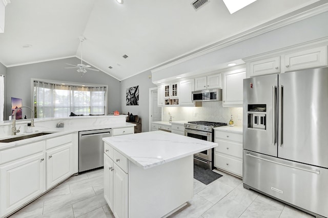 kitchen with stainless steel appliances, vaulted ceiling, light tile patterned floors, a kitchen island, and ceiling fan