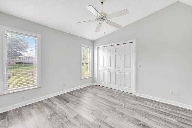 unfurnished bedroom featuring vaulted ceiling, a closet, ceiling fan, and light wood-type flooring