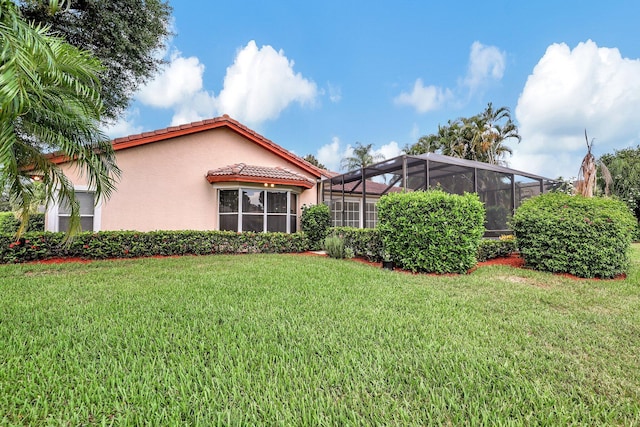 view of side of home featuring a lanai, stucco siding, a yard, and a tile roof