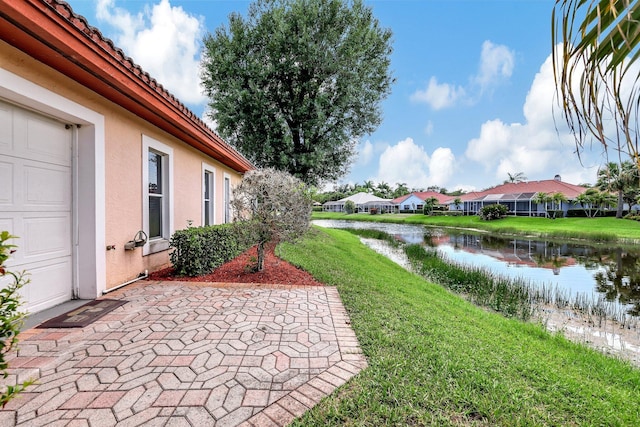 view of yard with a garage, a patio area, and a water view