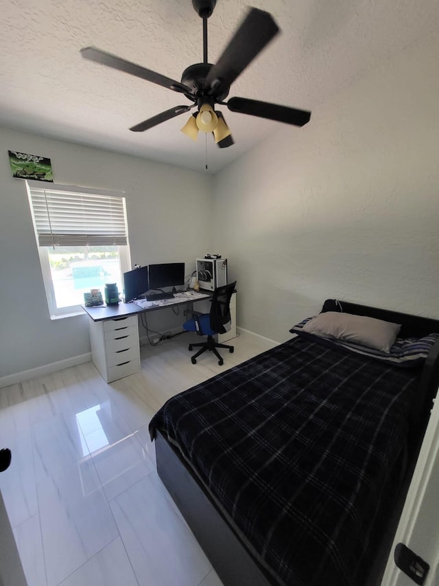 bedroom with ceiling fan and a textured ceiling