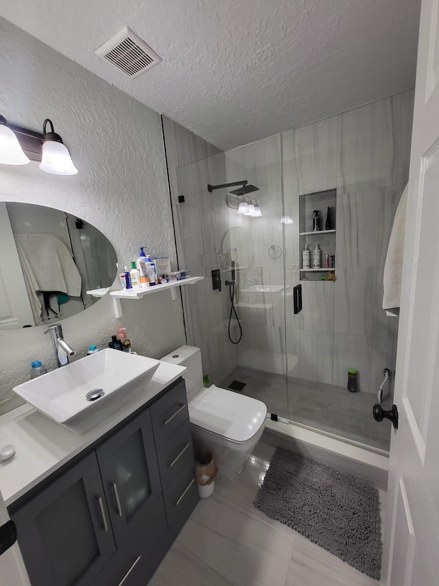 bathroom featuring tile patterned floors, walk in shower, vanity, a textured ceiling, and toilet