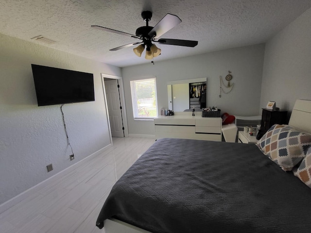 bedroom with ceiling fan and a textured ceiling