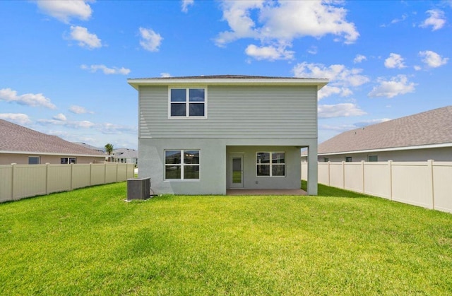 back of property with central AC and a lawn