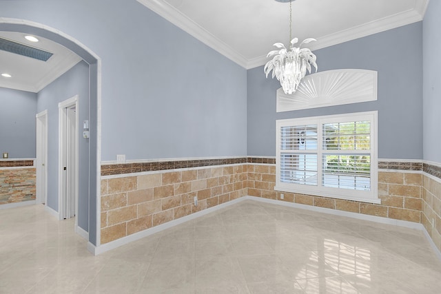 empty room featuring an inviting chandelier, tile walls, and crown molding