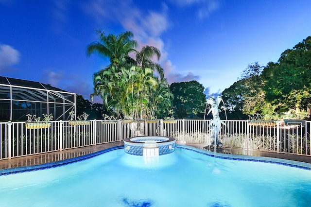 pool at dusk featuring an in ground hot tub