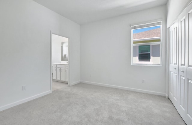 unfurnished bedroom with ensuite bath and light carpet