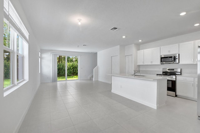 kitchen with a kitchen island with sink, white cabinetry, sink, and stainless steel appliances