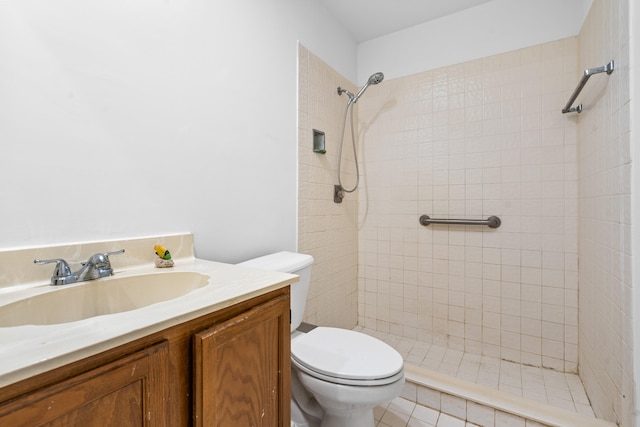 bathroom featuring a tile shower, tile flooring, vanity, and toilet