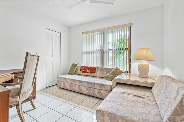 tiled living room with ceiling fan and a textured ceiling