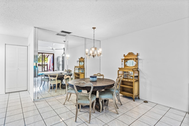 dining space featuring a textured ceiling, light tile floors, and ceiling fan with notable chandelier