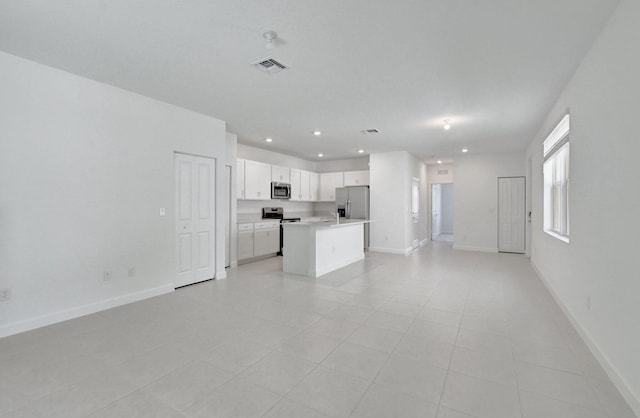 kitchen with a kitchen island with sink, white cabinets, light tile patterned floors, and appliances with stainless steel finishes