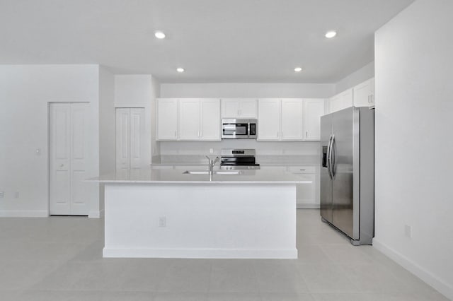 kitchen with white cabinets, stainless steel appliances, and a center island with sink