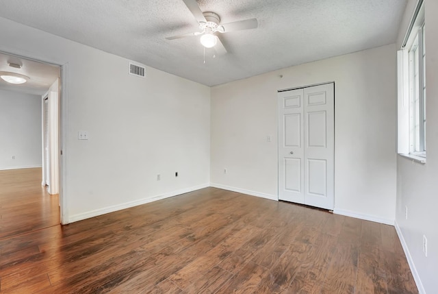 unfurnished bedroom with ceiling fan, a textured ceiling, dark hardwood / wood-style floors, and a closet