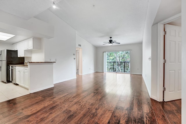 unfurnished living room with ceiling fan, lofted ceiling, and light wood-type flooring