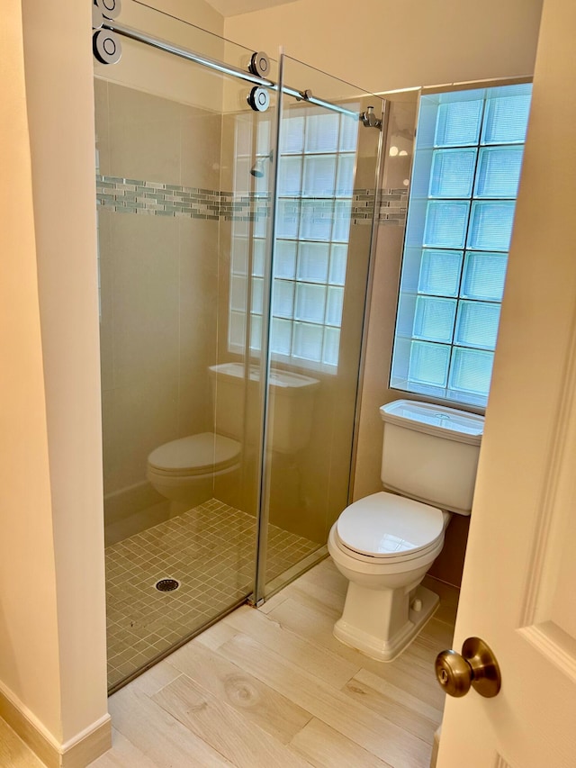 bathroom featuring tile patterned floors, toilet, an enclosed shower, and plenty of natural light