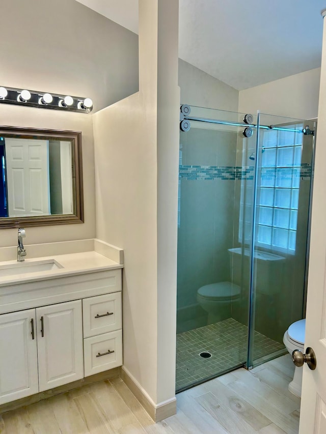 bathroom featuring vanity, toilet, and a shower with door