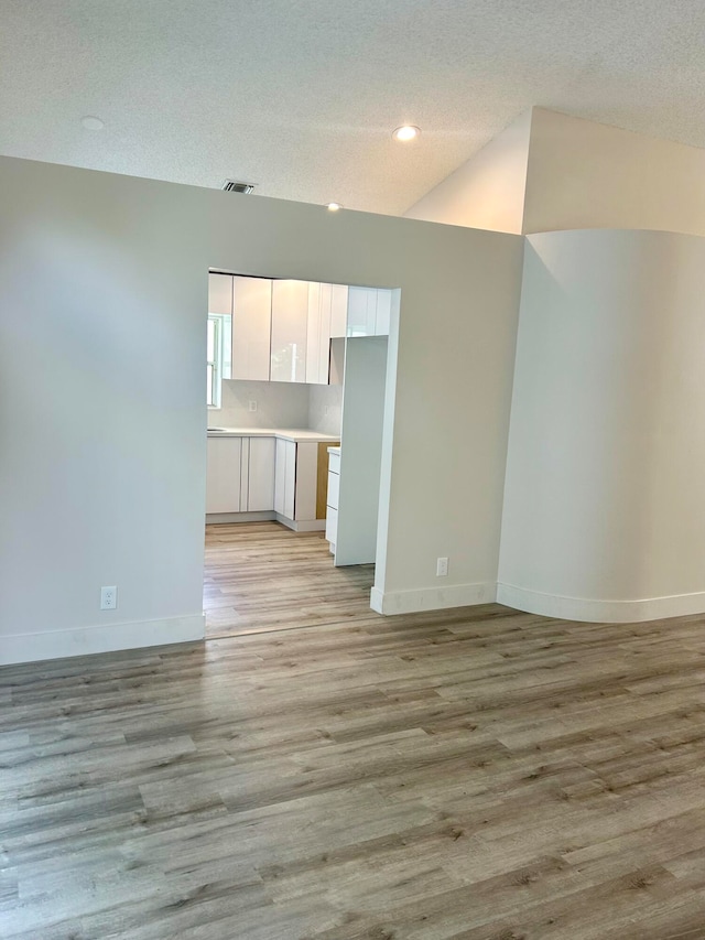 unfurnished living room with light hardwood / wood-style flooring and a textured ceiling