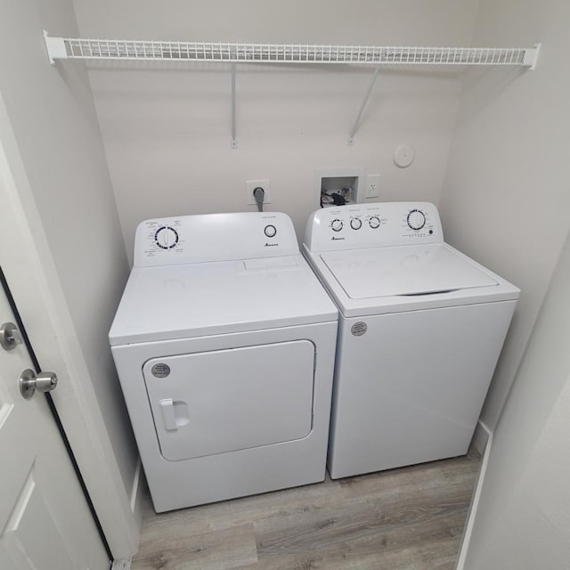 laundry room featuring washing machine and clothes dryer and light hardwood / wood-style flooring