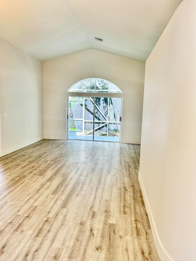 unfurnished room with lofted ceiling and light hardwood / wood-style flooring