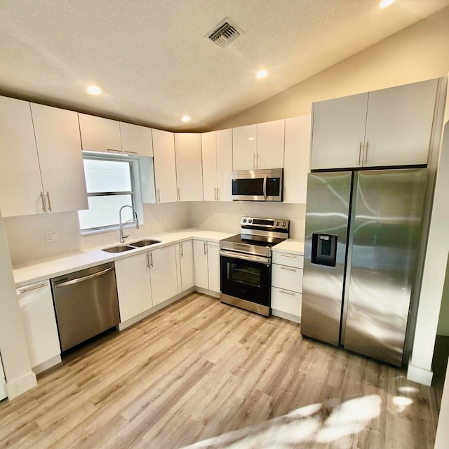 kitchen with lofted ceiling, sink, light hardwood / wood-style flooring, and stainless steel appliances