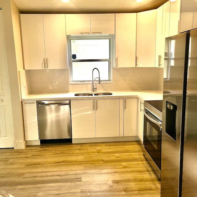 kitchen with sink, tasteful backsplash, light wood-type flooring, and stainless steel appliances