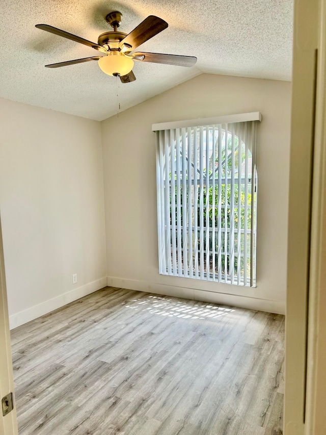 empty room featuring a textured ceiling, light hardwood / wood-style flooring, lofted ceiling, and ceiling fan